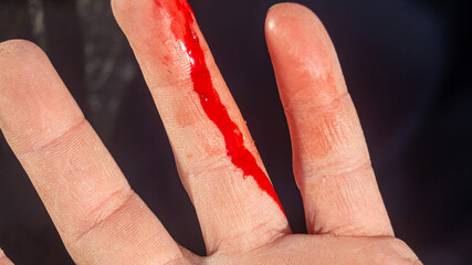 Finger in blood. Bloody finger. Close-up of a drop of blood running down a finger