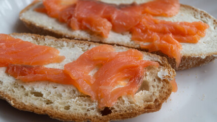 Sandwiches with cream cheese and sliced ​​salmon on a plate. Sliced ​​pieces of salmon on...