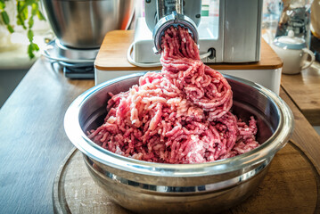 Meat grinder machine chopping uncooked red ground meat. Professional kitchen appliance