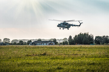 Fototapeta premium Military large aircraft helicopter flies over green field
