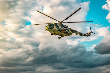 Military large helicopter aircraft flies in cloudy sky