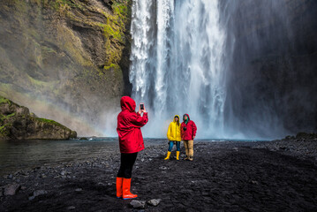 Photographing people in bright clothes in front of the Skogafoss waterfall in Iceland