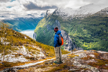 Tourist man standing on the rock over Geiranger fjord, Norway