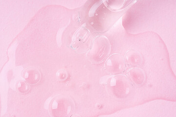 Macro shot of serum flows from pipette on pink background.