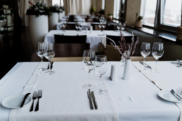 The restaurant features a stylish and contemporary interior complete with elegant table settings and vibrant plants.