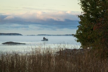 Serene lakeside scene with boat and mist.