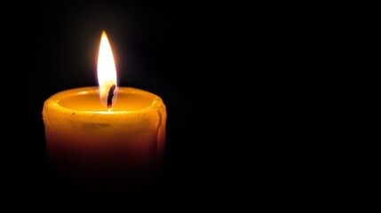 One lit candle burns brightly on a black background