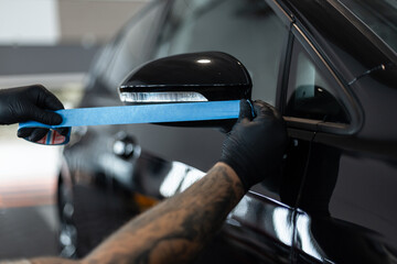 professional man tapes a car with masking tape before polishing. Preparation before polishing