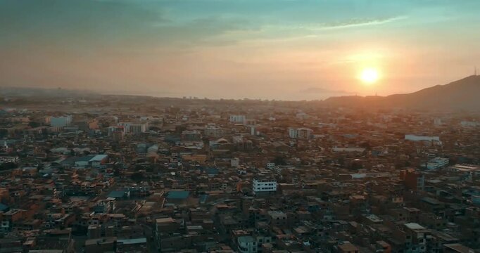 Beautiful great general shot of a sunrise with the rising sun of a poor village on the outskirts and north side of the city of Lima, Peru. The distrito of Puente Piedra recorded with a drone.