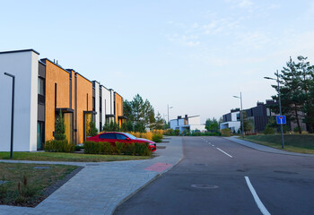 Townhouse in residential district. New apartment buildings in green enviroment. Street with Townhouse along asphalt road in gated community. Car on parking at house. Modern Townhouses in suburban.