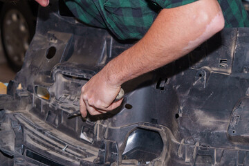 Mechanic working on car part with screwdriver