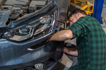 Mechanic aligning car bumper in workshop