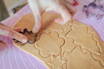 The process of making homemade Christmas cookies in real life. Roll out the dough. Cut cookies with molds from the dough. Homemade gingerbread cookies. Hands at work. Christmas mood. Ordinary people.