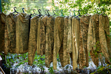 Team paintball, equipment selection, paintball uniform. Camouflage paintball equipment outdoors hanging on a rope against a bokeh background. Paintball in nature.