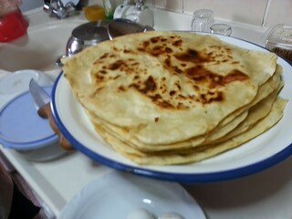 A plate of freshly made flatbreads, their golden-brown spots reflecting the warmth and tradition of homemade food, symbolizing the comfort and simplicity of traditional cuisine shared among family.