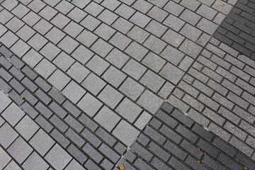 Texture of square paving tile. Pattern of gray tiles in the street. Concrete pavers with autumnal leaves close up background.