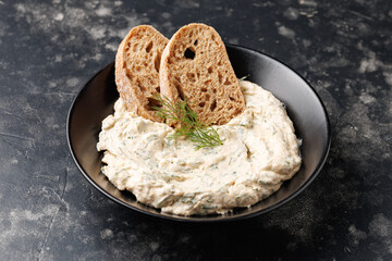 smoked salmon and soft cream cheese pate or mousse in black bowl served with baguette toasts