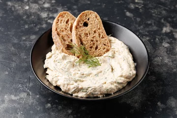 smoked salmon and soft cream cheese pate or mousse in black bowl served with baguette toasts © Maksims