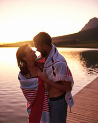 Hug, sunset or couple with towel at lake together on vacation, anniversary and outdoor holiday....