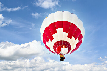 Colorful hot air balloon flying over blue sky with white clouds