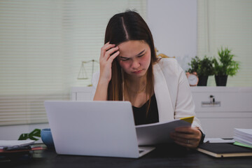 An Asian businesswoman sits at her desk, overwhelmed by deadlines and responsibilities. Her brow...