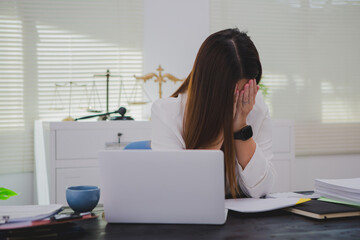 An Asian businesswoman sits at her desk, overwhelmed by deadlines and responsibilities. Her brow...