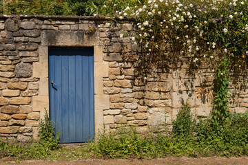 Rear view of a walled cottage garden with an ancient stone wall and an wooden door