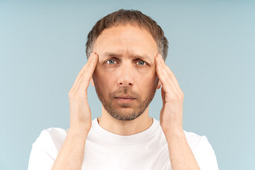 Weary sick man holds temples, troubled by headache, suffering migraine from sleeping disorder or...