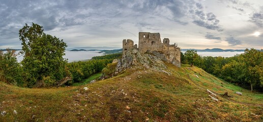 Panorama autumn landscape with the ruins of an old castle and fog at sunrise. Coming autumn, autumn morning