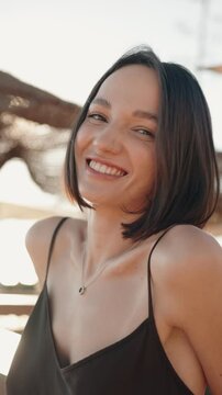 Slow motion close up of attractive young woman with bob haircut smiling happily at the camera during a sunny day. Happiness, youth and beauty concept.