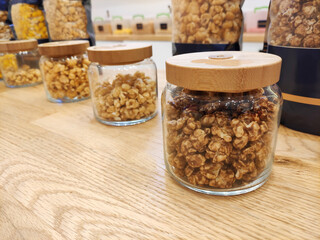 Sweet fried multicolored airy popcorn in glass jars on the shop window