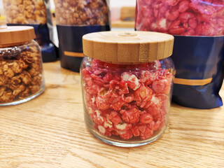 Sweet fried multicolored airy popcorn in glass jars on the shop window