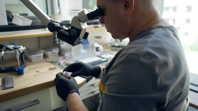 professional laboratory for the production of dental protozoa veneers and crowns male specialist polishes the shape of tooth through magnifying lenses