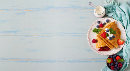 Crepes, thin pancakes  with yogurt and berries. Healthy food for breakfast. Top view with copy space