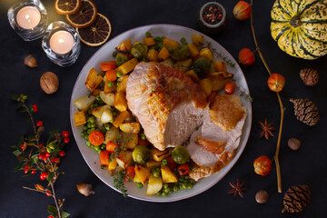 Roasted rolled and boned turkey breast fillet with potatoes, carrots, turnip and brussel sprouts. Thanksgiving autumn dinner table with decorations. View from above