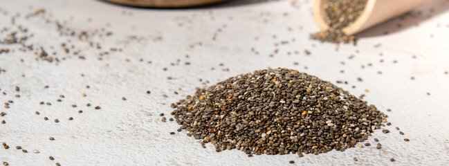 Heap of Chia seeds with wooden spoon. Healthy superfood rich in Omega 3 fatty acids. Dry healthy natural ingredient. Chia grains are falling. Vegetarian food 