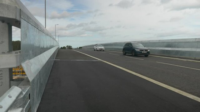 Fly Over Bridge with Road and Cars Passing Metal Barriers on Side Cloudy Day