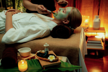 Serene ambiance of spa salon, woman customer indulges in rejuvenating with luxurious face cream massage with warm lighting candle. Facial skin treatment and beauty care concept. Quiescent