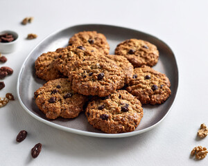 A pile of vegan oatmeal cookies with chocolate chips and walnuts, featuring a clean white backdrop, ai.