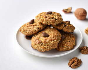 A stack of freshly baked vegan oatmeal cookies with nuts and raisins on a white background, ai.