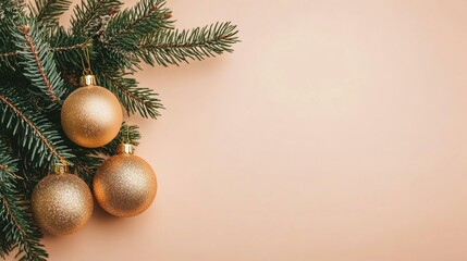 Christmas tree branch with golden baubles on soft pink background.