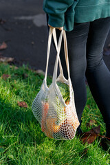 Woman Holding reusable Mesh grocery shopping Bag with Fresh Vegetables and fruits. Eco-friendly bag filled with fresh produce held by a person