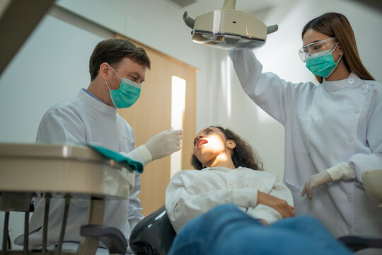 A dentist and nurse collaboration curing patient teeth in a modern clinic. concepts: Teamwork of dental with oral of patient with care .