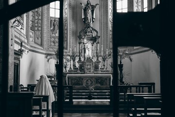 Nun praying in a historic church with ornate altar.