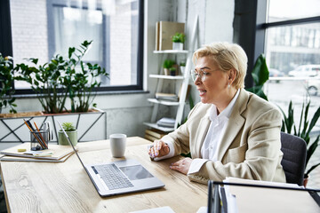 An adult woman in fashionable clothing participates in a virtual discussion at a well lit desk.