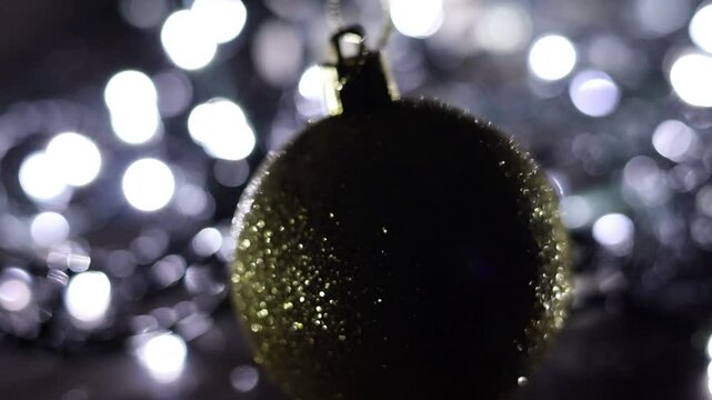 Una toma de cerca de una bola de navidad dorada rodeada de luces de varios colores con un fondo desenfocado.  Decoraci&oacute;n de navidad y fin de a&ntilde;o