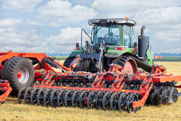 Fototapeta premium Farm machinery working in a vibrant landscape during a sunny day under blue skies