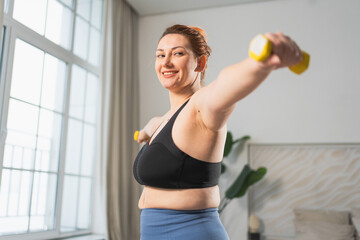 Fitness workout training. Woman picking up dumbbells. Plus size female doing sports exercise at...