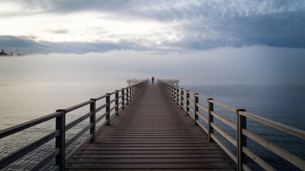 Fototapeta premium A person walking on a wooden pier by the sea on a sunny summer day