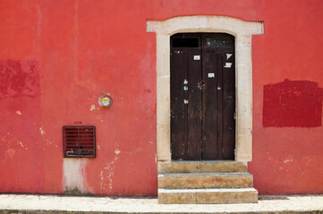 Rustic wood door in red wall, white stone trim, colonial Valladolid charm